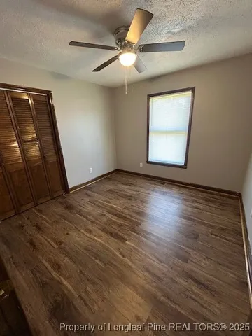an empty room with wooden floor fan and windows