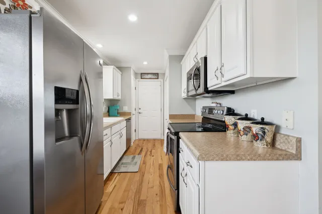 a kitchen with stainless steel appliances granite countertop a refrigerator a sink a stove and white cabinets