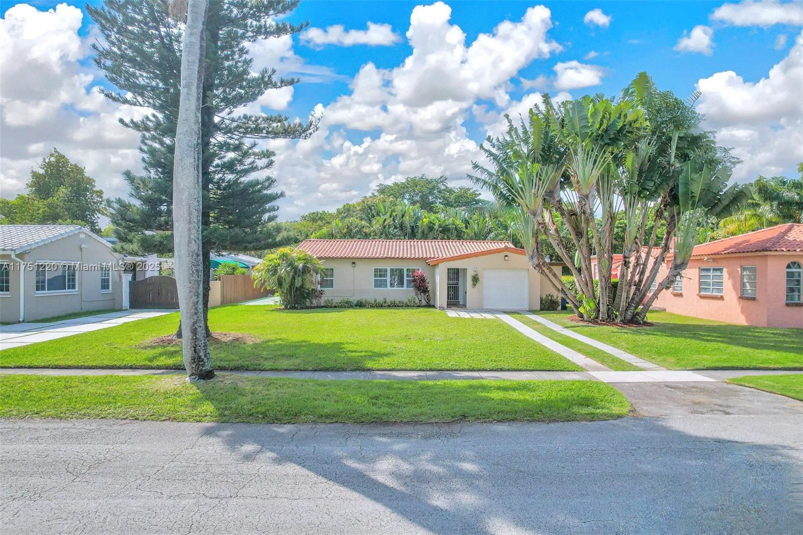 a view of a house with a big yard plants and large trees