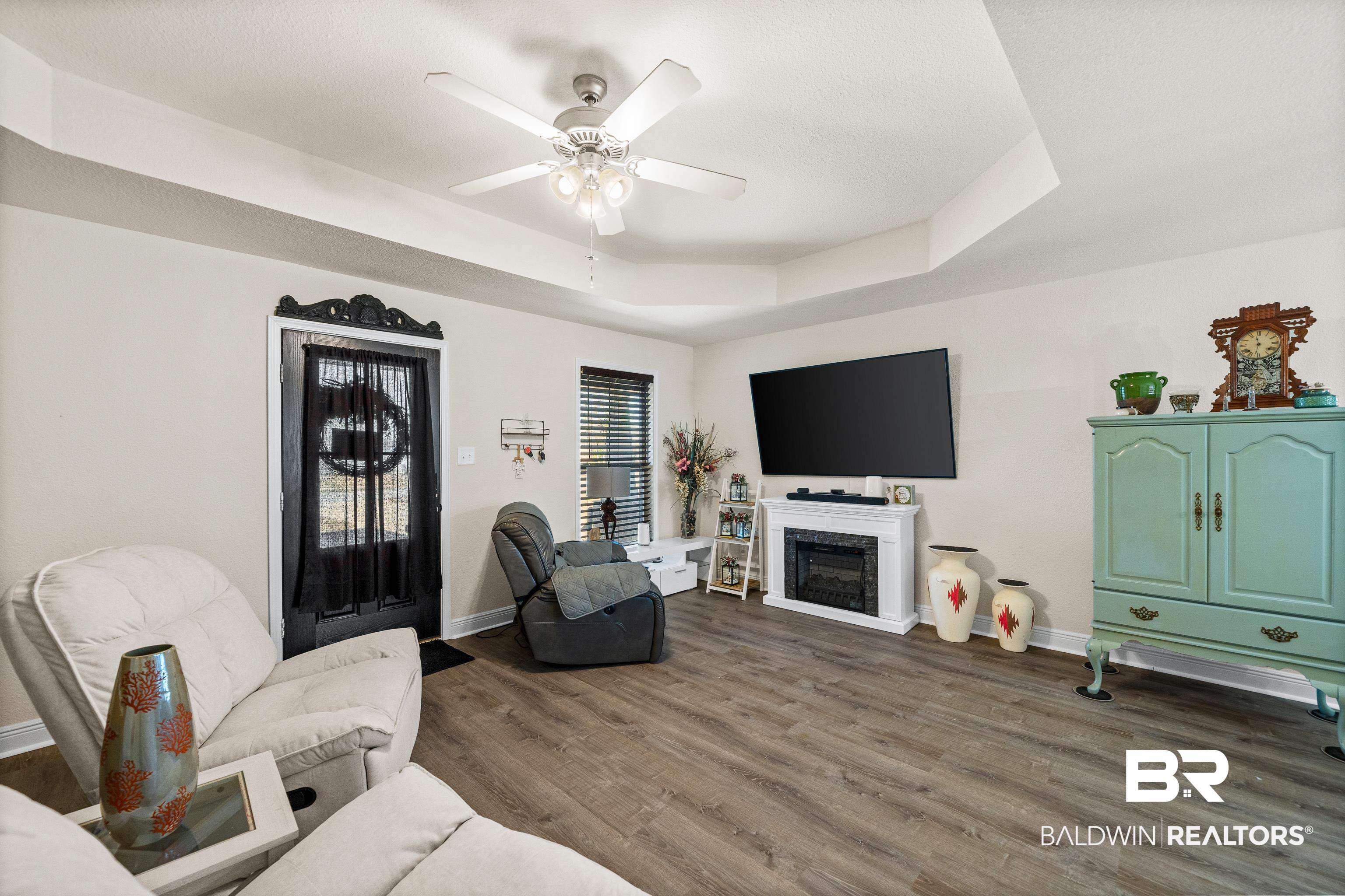 17100 Cold Mill Loop Foley, AL 36535 - Photo 5 of 27 Living room featuring a fireplace, dark wood-style floors, a tray ceiling, and ceiling fan