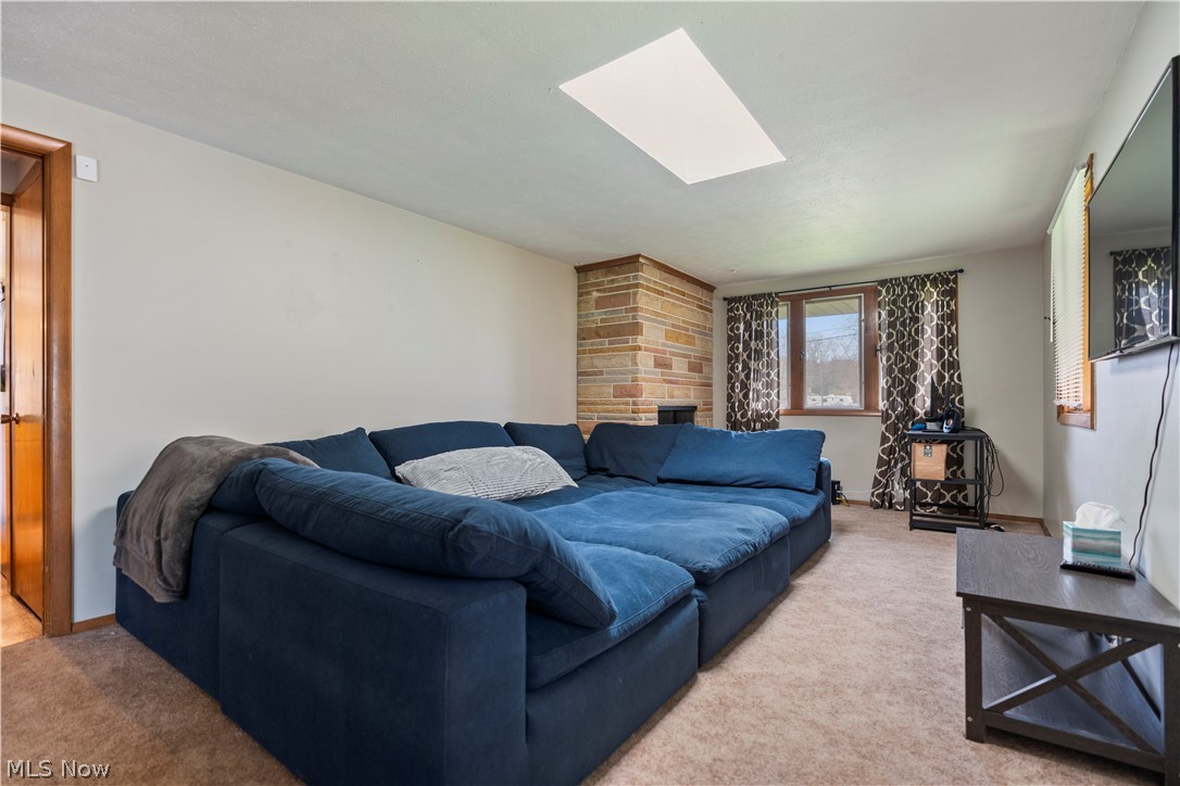 4904 3rd Street Northwest Canton, OH 44708 - Photo 16 of 31 Carpeted living room with a stone fireplace and a skylight