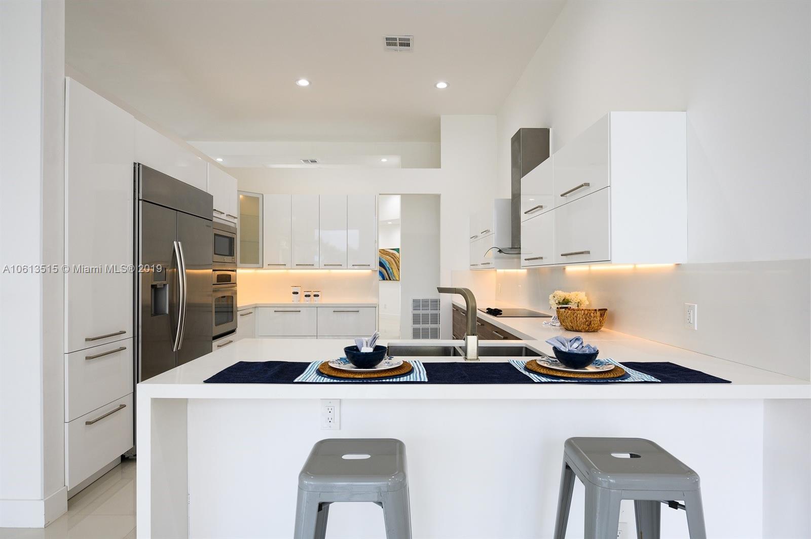 561 Ranch Road Weston, FL 33326 - Photo 13 of 46 a kitchen with a refrigerator a stove and white cabinets