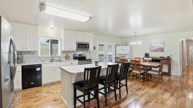 a kitchen with stainless steel appliances a dining table chairs stove refrigerator and cabinets
