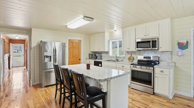 a kitchen with stainless steel appliances granite countertop a stove top oven a sink dishwasher and wooden cabinets with wooden floor