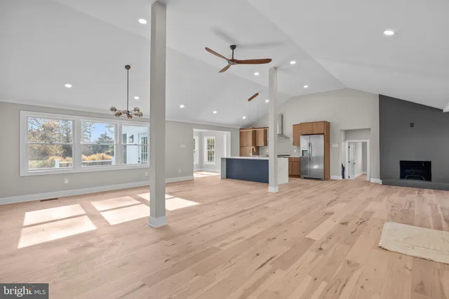 a view of an empty room with wooden floor and a kitchen
