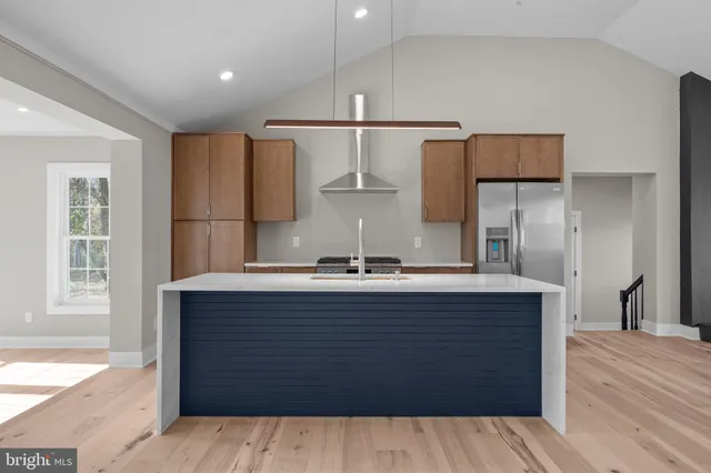 a kitchen with kitchen island stainless steel appliances a sink stove refrigerator and cabinets