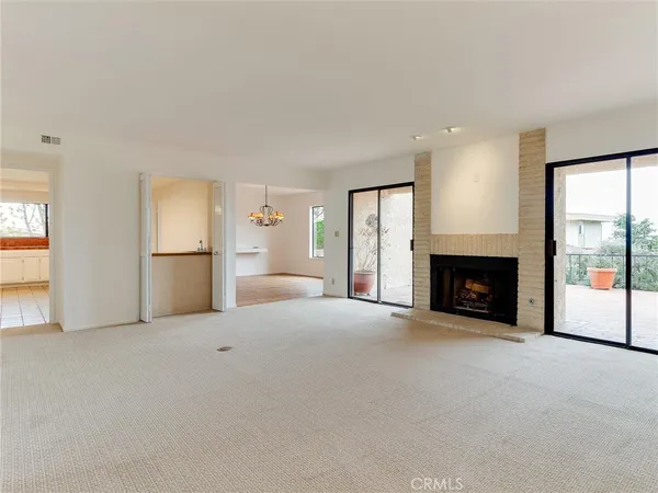 an empty room with windows and fireplace