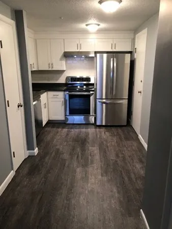 a kitchen with granite countertop a refrigerator and a stove top oven