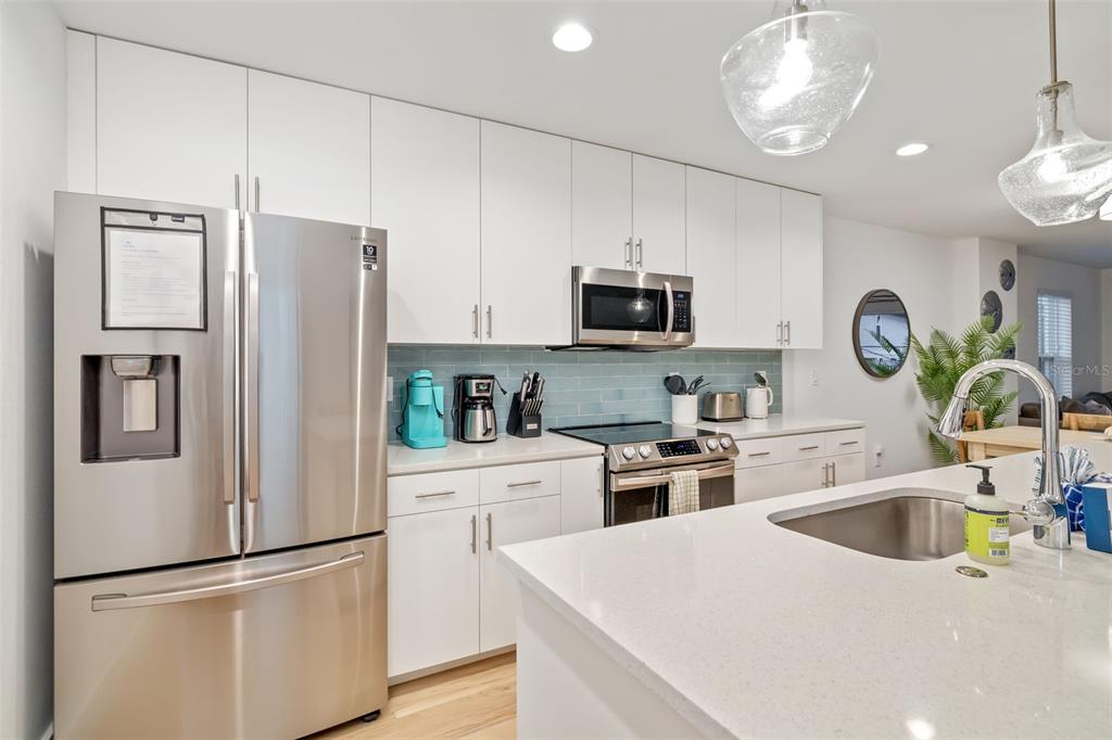 15305 1st Street East, Unit 201 Madeira Beach, FL 33708 - Photo 21 of 41 a kitchen with refrigerator a sink and white cabinets