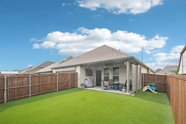 a view of a backyard with couches plants and large tree