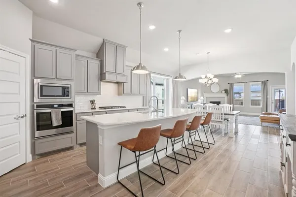 a kitchen with stainless steel appliances granite countertop a stove a sink a refrigerator and a dining table with wooden floor