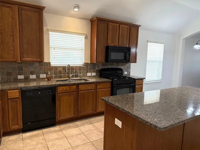 a kitchen with granite countertop a sink a stove a microwave and wooden cabinets