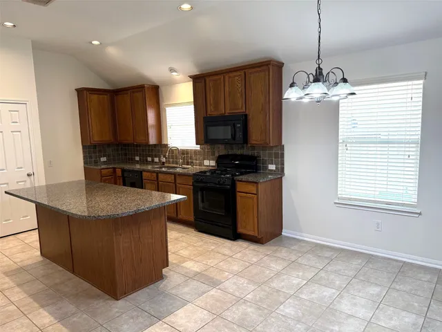 a kitchen with stainless steel appliances granite countertop a stove a sink a microwave and a refrigerator