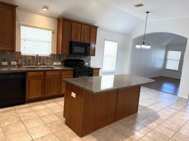 a kitchen with stainless steel appliances granite countertop a stove a sink a counter top space and a window