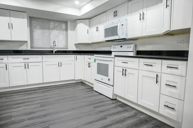 a kitchen with stainless steel appliances granite countertop white cabinets granite counter tops and a hard wood floors