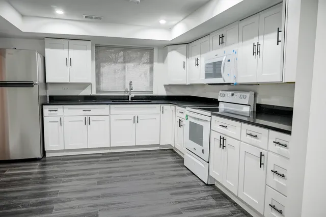 a white kitchen with granite countertop stainless steel appliances