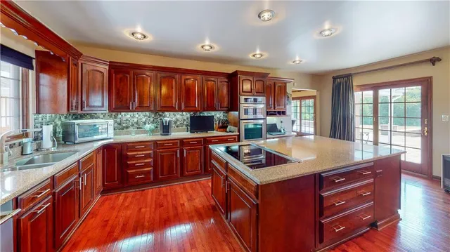 a kitchen with stainless steel appliances granite countertop a refrigerator a stove and a sink with wooden floor