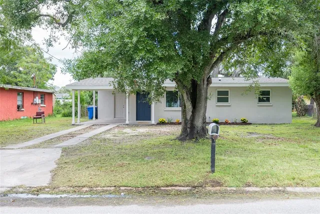 a view of a house with a yard and large tree
