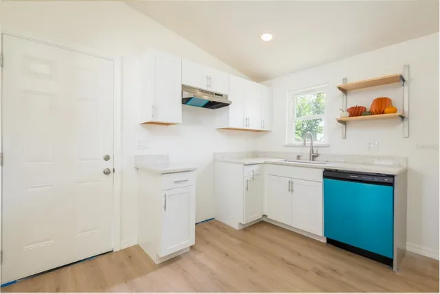 a kitchen with white cabinets and sink