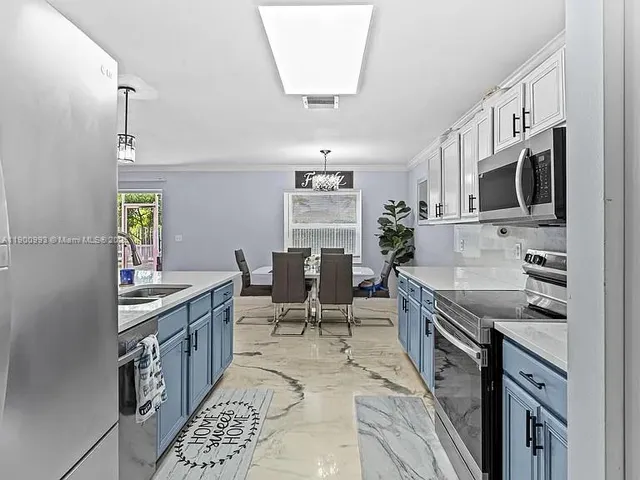 a kitchen with stainless steel appliances granite countertop a stove top oven a sink dishwasher a dining table and chairs with wooden floor