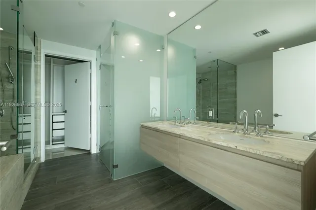 a bathroom with a granite countertop sink a large mirror and a shower