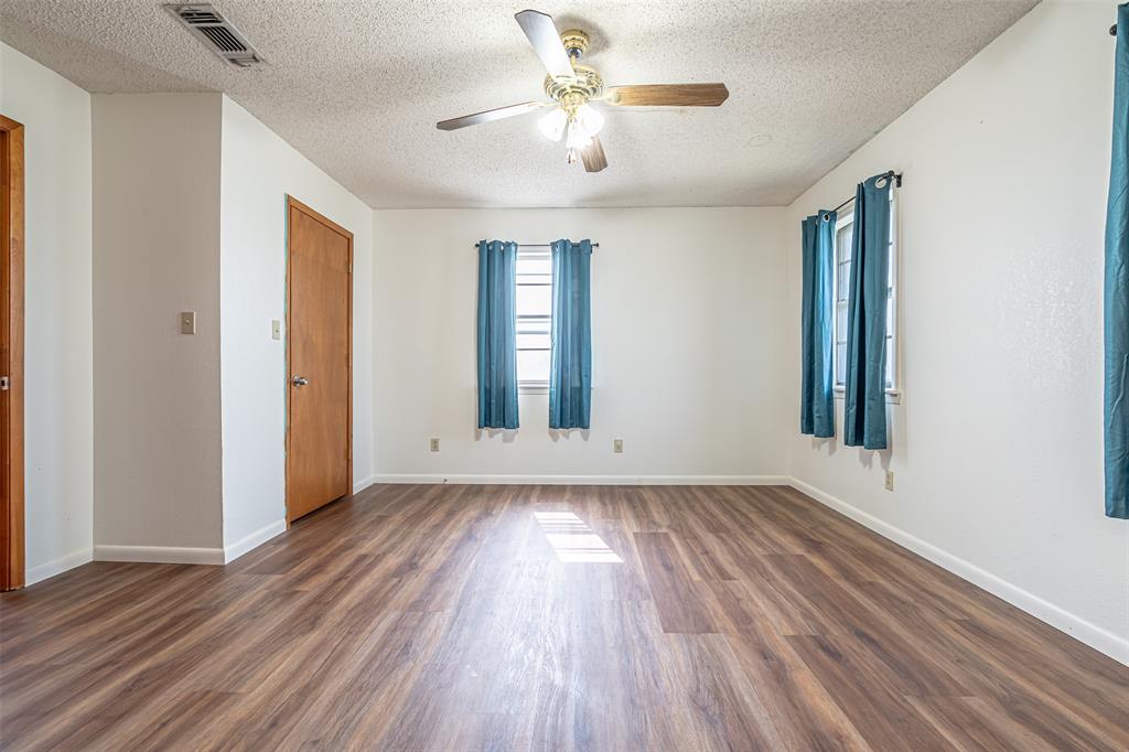 501 Endora Dublin, TX 76446 - Photo 23 of 39 an empty room with wooden floor chandelier fan and windows