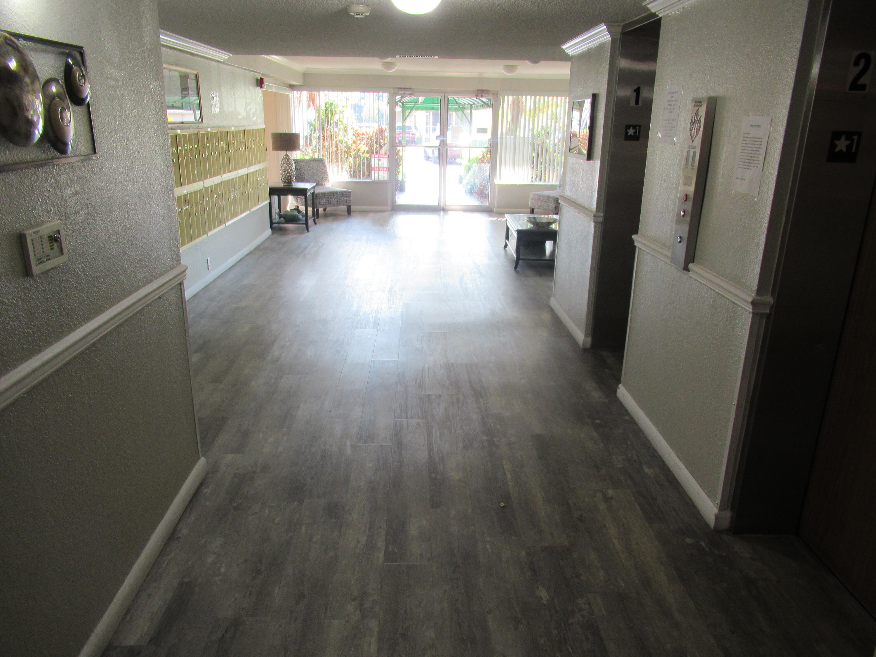 22605 Southwest 66th Avenue, Unit 410 Boca Raton, FL 33428 - Photo 20 of 28 a view of a hallway with wooden floor and furniture