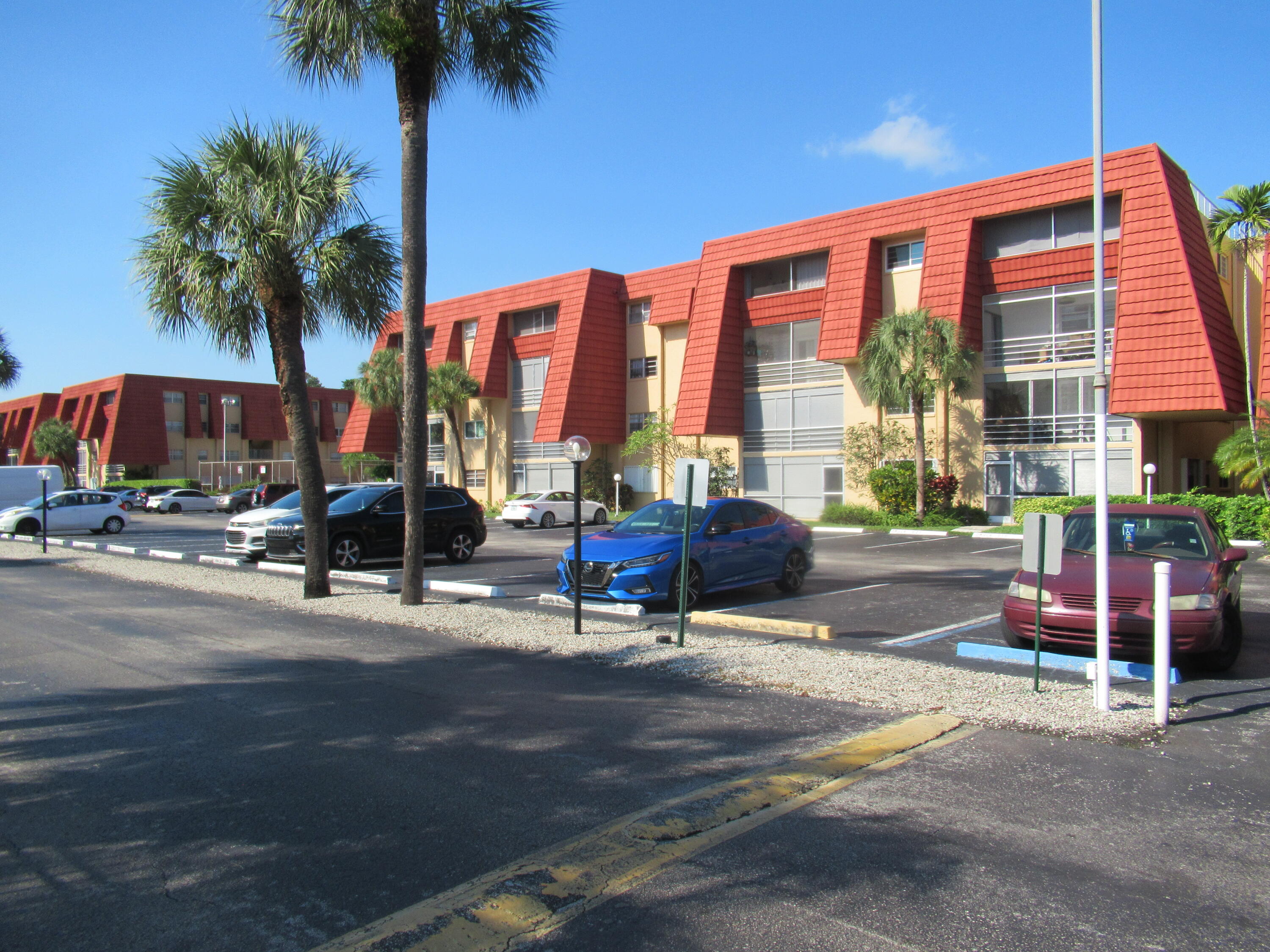 22605 Southwest 66th Avenue, Unit 410 Boca Raton, FL 33428 - Photo 23 of 28 a row of palm trees in front of a building
