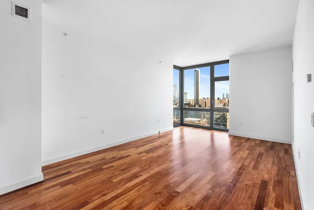 a view of a kitchen and an empty room with wooden floor