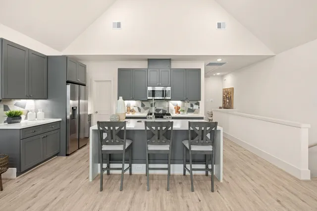 a kitchen with cabinets a sink dishwasher a dining table and chairs with wooden floor
