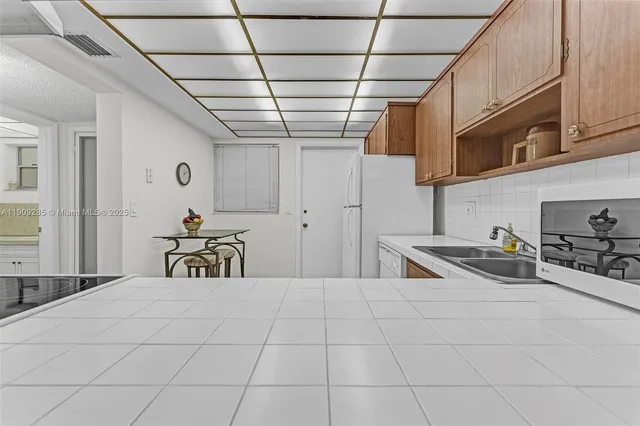 a room with lots of white furniture and a refrigerator