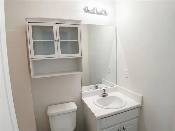 a bathroom with a toilet sink vanity and mirror