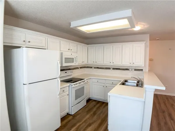 a kitchen with a refrigerator a stove top oven a sink and cabinets