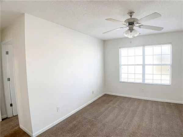 an empty room with windows and fan