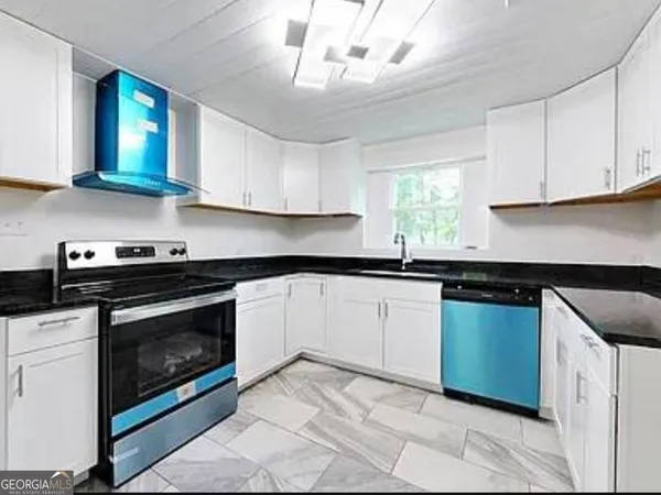a kitchen with granite countertop a stove sink and cabinets