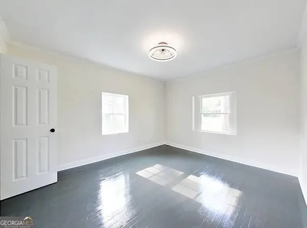 an empty room with wooden floor and windows