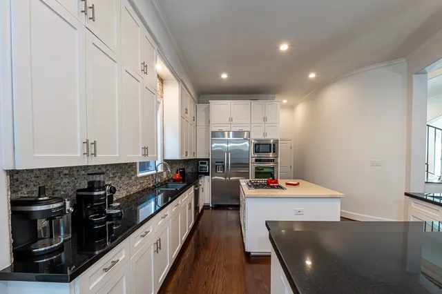 a kitchen with stainless steel appliances a stove a sink a refrigerator and white cabinets