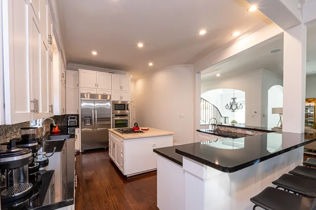 a kitchen with a stove a sink dishwasher and a dining table with wooden floor