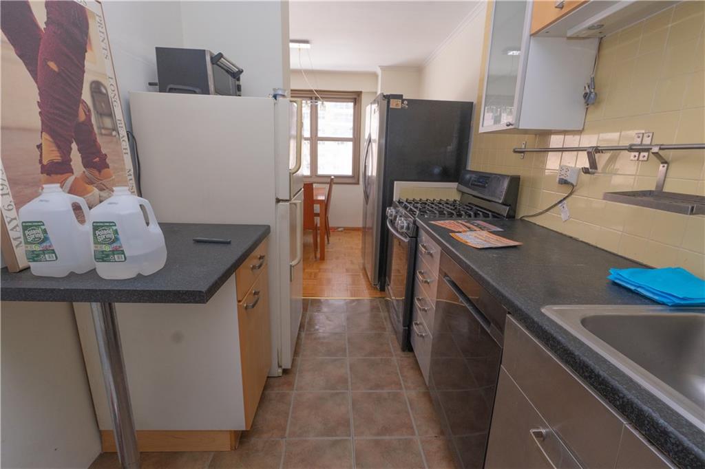 458 Neptune Avenue, Unit 3H Brooklyn, NY 11224 - Photo 2 of 3 a kitchen with stainless steel appliances a stove a sink a refrigerator and wooden floor