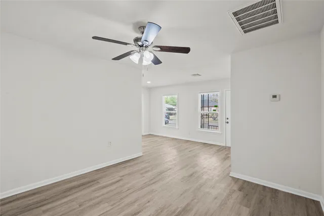 a view of an empty room with a window and wooden floor