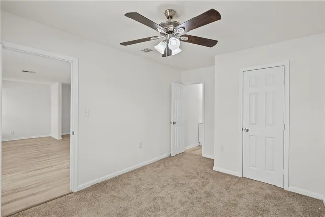a view of an empty room and chandelier fan
