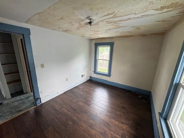 an empty room with wooden floor and windows
