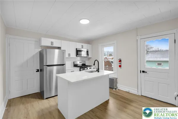 a view of a kitchen with refrigerator and wooden floor