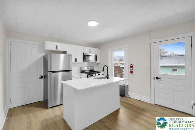a view of a kitchen with refrigerator and wooden floor