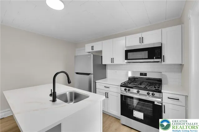a kitchen with stainless steel appliances a stove a sink and white cabinets