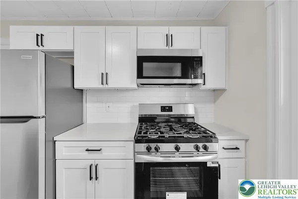 a kitchen with stainless steel appliances granite countertop white cabinets a stove a microwave and a refrigerator