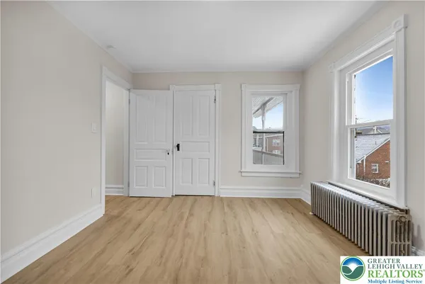 a view of an empty room with wooden floor and a window