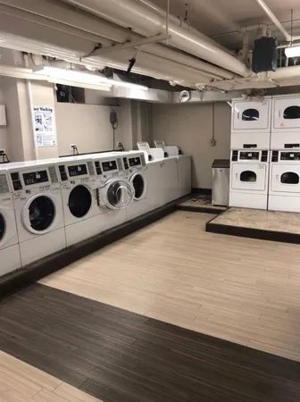 a utility room with stainless steel appliances wooden floors and white walls
