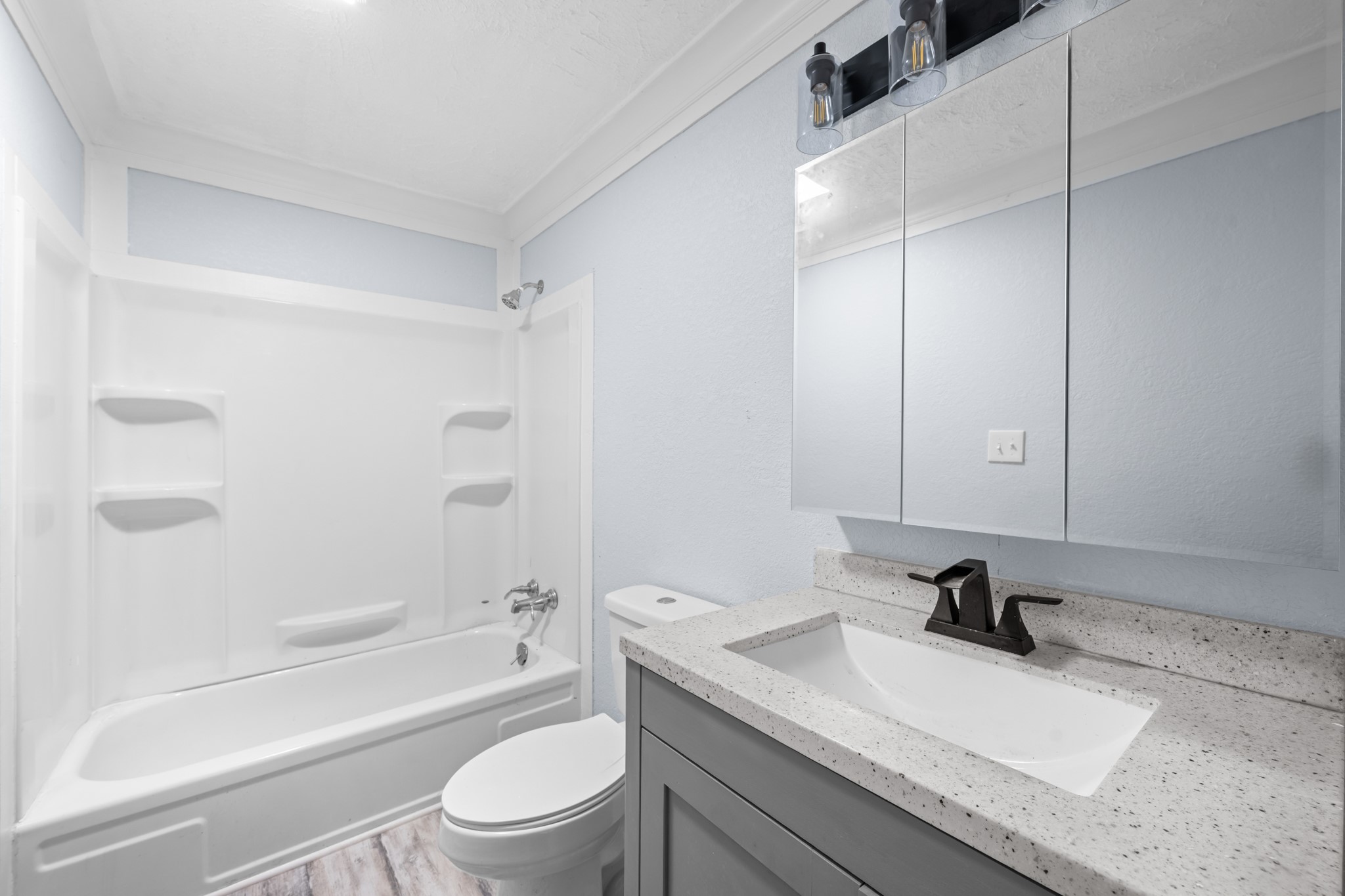 2534 Bastrop Angleton, TX 77515 - Photo 26 of 50 Updated secondary bathroom featuring a modern vanity with solid-surface countertops, updated fixtures, and a tub/shower combination with built-in shelving. Bright neutral finishes create a clean and functional space designed for everyday convenience.