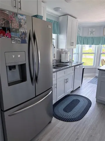 a kitchen with stainless steel appliances granite countertop a refrigerator a sink a stove a washer dryer and a dining table